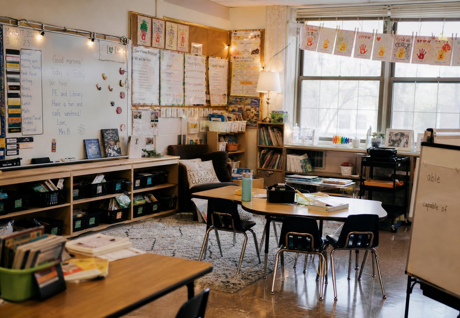 A real elementary school classroom with natural window light, children's artwork on the walls, a reading corner, and small group tables